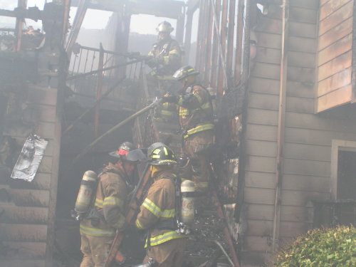 Firemen crew working on burning house smoking.