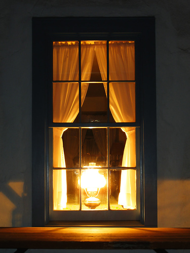 Vintage lamp burning in window. 