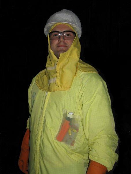 A Nuclear Engineer in a yellow protective suit standing at night.