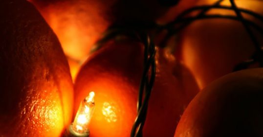 On Christmas Eve, a manvotional scene is created as a group of oranges are lit up with a candle.