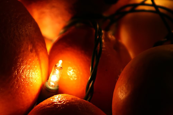 On Christmas Eve, a manvotional scene is created as a group of oranges are lit up with a candle.