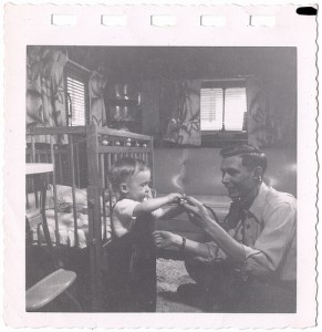 A man is teaching his son, holding him in a crib.
