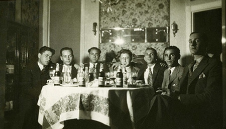 A classy group of men sitting around a table at a bachelor party.
