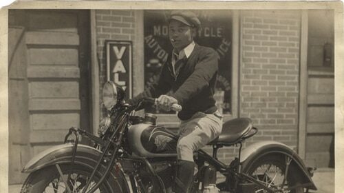 An old photo of a man being on a motorcycle.