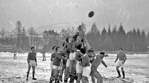 A group of men playing the game of rugby in the snow.