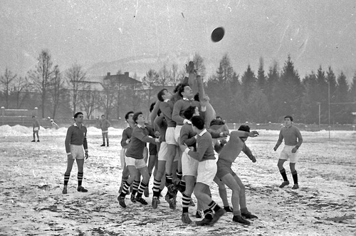 A group of men playing the game of rugby in the snow.