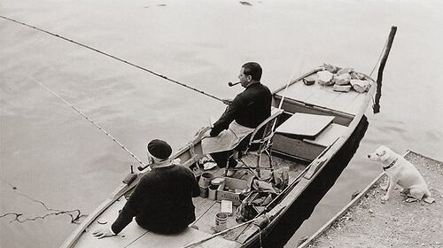 Two men and their dog enjoy a peaceful fishing trip in a boat.
