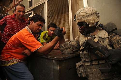 A man doing arm wrestling with soldier.