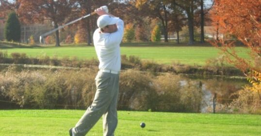 A golf pro swinging a golf club on a golf course.