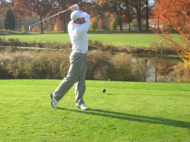 A golf pro swinging a golf club on a golf course.