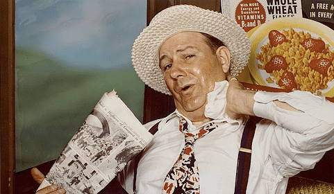 A man wearing a hat carries a handkerchief.