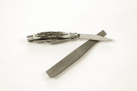 A sharpened pocket knife with a blade on a white background.