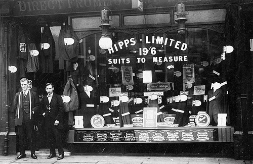 Vintage men standing near tailor shop.