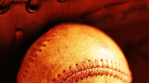 A baseball is resting in a well-worn baseball glove.