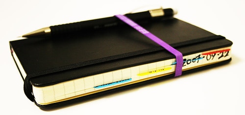 Moleskin notebook and pen fitted with ribbon.