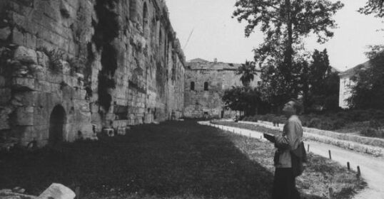 An old black and white photo of a man experiencing the world as he walks down a path.