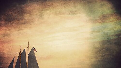 A sailboat gracefully glides across the vast ocean, capturing the beauty of a breathtaking sunset.