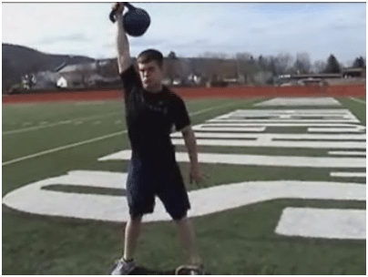 Man doing kettlebell bend up exercise in the ground.