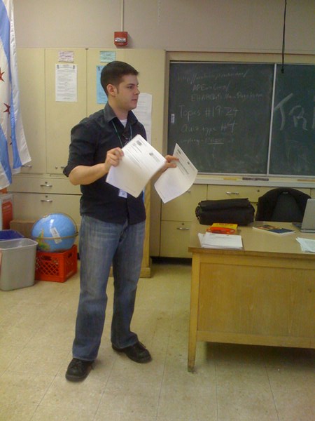 Aaron Kurtz standing in the classroom and holding papers.