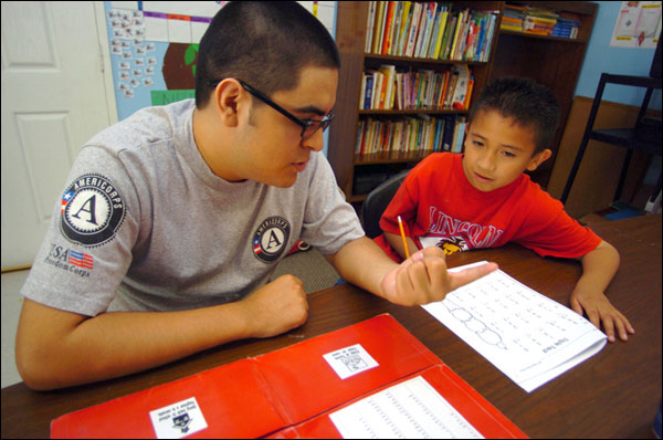 Americorps employee working with young student.