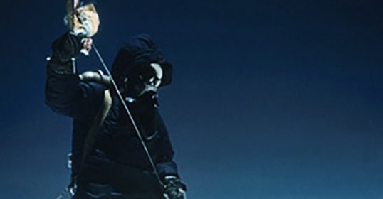 A man in a gas mask standing on top of a mountain, experiencing an adventure.