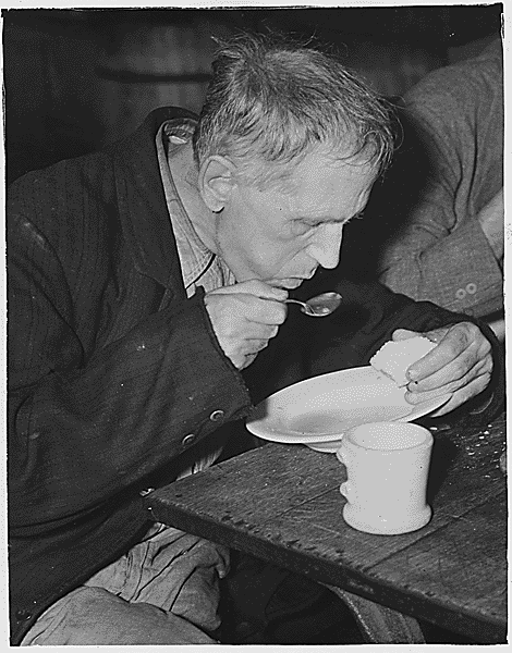 Vintage homeless man eating soup.