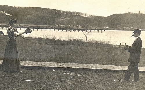 Vintage Victorian couple playing catch on the side of river.