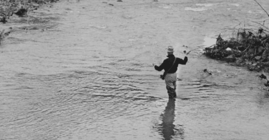 A man wading through a flooded river, with a determined mind.