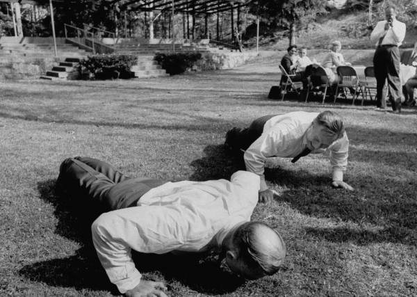 Two men performing ultimate push-up exercises in the grass.