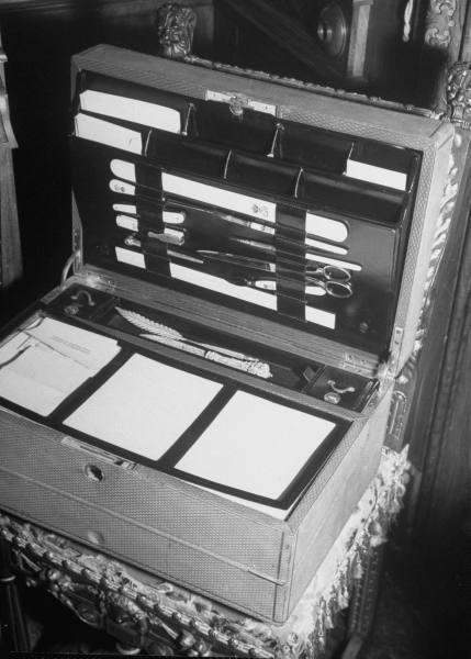 An artistic black and white photograph of a briefcase containing various papers.