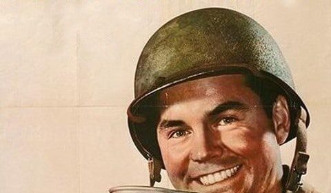 A man in a military uniform is holding a perfect cup of coffee.