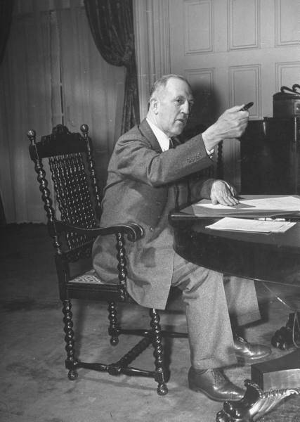 A decisive man in a suit sitting at a desk.