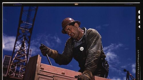 A construction worker is paying their dues as they work on an important piece of wood.