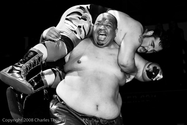 King Dabada screaming while lifting wrestler in match.