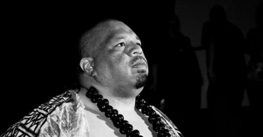 A black and white photo of a professional wrestler in a Hawaiian outfit.
