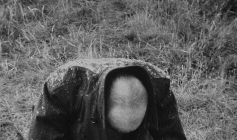 Black and white photograph of a man dealing with male depression while kneeling in the grass.