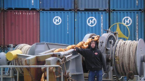 A man standing in front of a massive freighter ship.