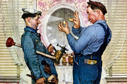 Two plumbers in overalls are talking to each other as they unclog a toilet.