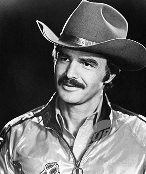 Burt Reynolds wearing cowboy hat showing mustache.