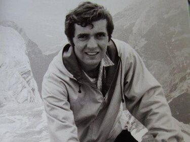 An old photo of a man on top of a rock.