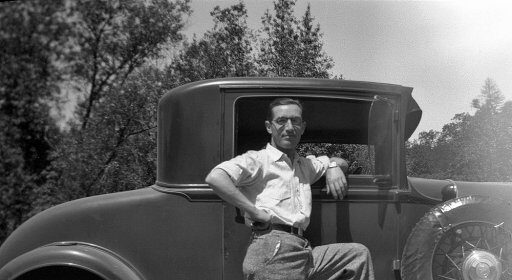 A man leaning against a car, giving us a casual pose.