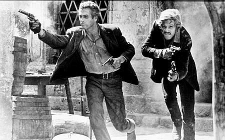 Two buddies with guns in a movie scene.