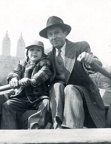A man in a hat imparts advice to his son in a boat.