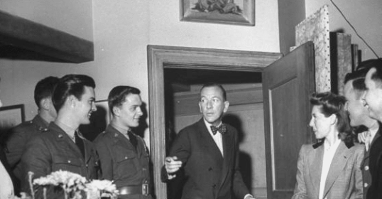 An old black and white photo of a group of people standing in a room.