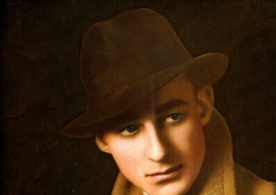 A man in a hat and coat showcasing the art of pipe smoking, serving as a primer for Pipe Smoking 101.