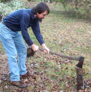 Man cutting off the firewood with axe.