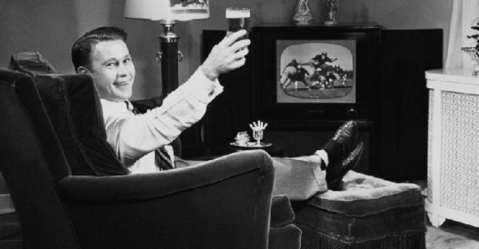 A man sitting in a chair with a beer in his hand.