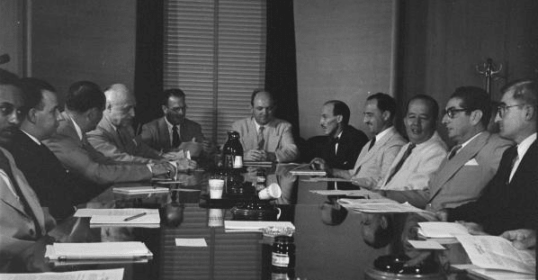 A group of men sitting around a table having a meeting.