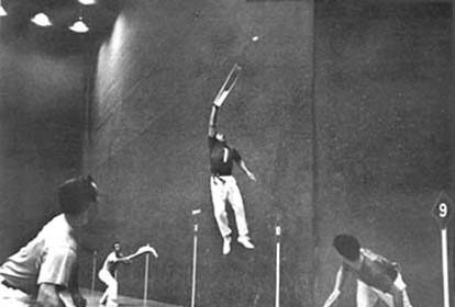 A black and white photo of a group of men playing **badminton**.