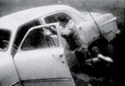 An old black and white photo of a man escaping from a sinking car.